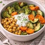 Bowl tibio de brócoli, zanahoria y calabacita asadas con garbanzos, coronado con una cucharada de yogur de limón