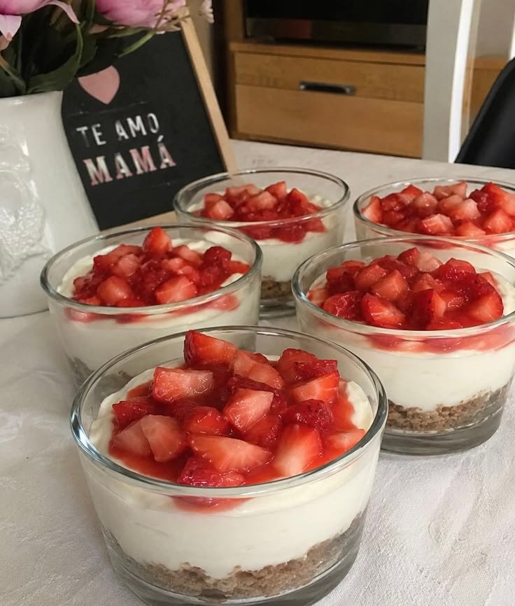 Mini cheesecakes de fresa en vasos con base de galleta, relleno cremoso blanco y fresas picadas encima