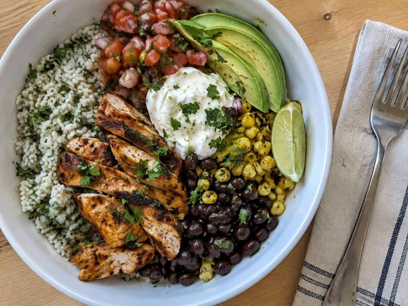 Burrito bowl de pollo al chipotle con arroz cilantro-limón, frijoles negros, elote, pico de gallo y aguacate, receta saludable fácil
