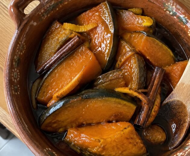 Gajos de calabaza en tacha ligera brillantes en almíbar de piloncillo con canela y naranja servidos en cazuela de barro casera
