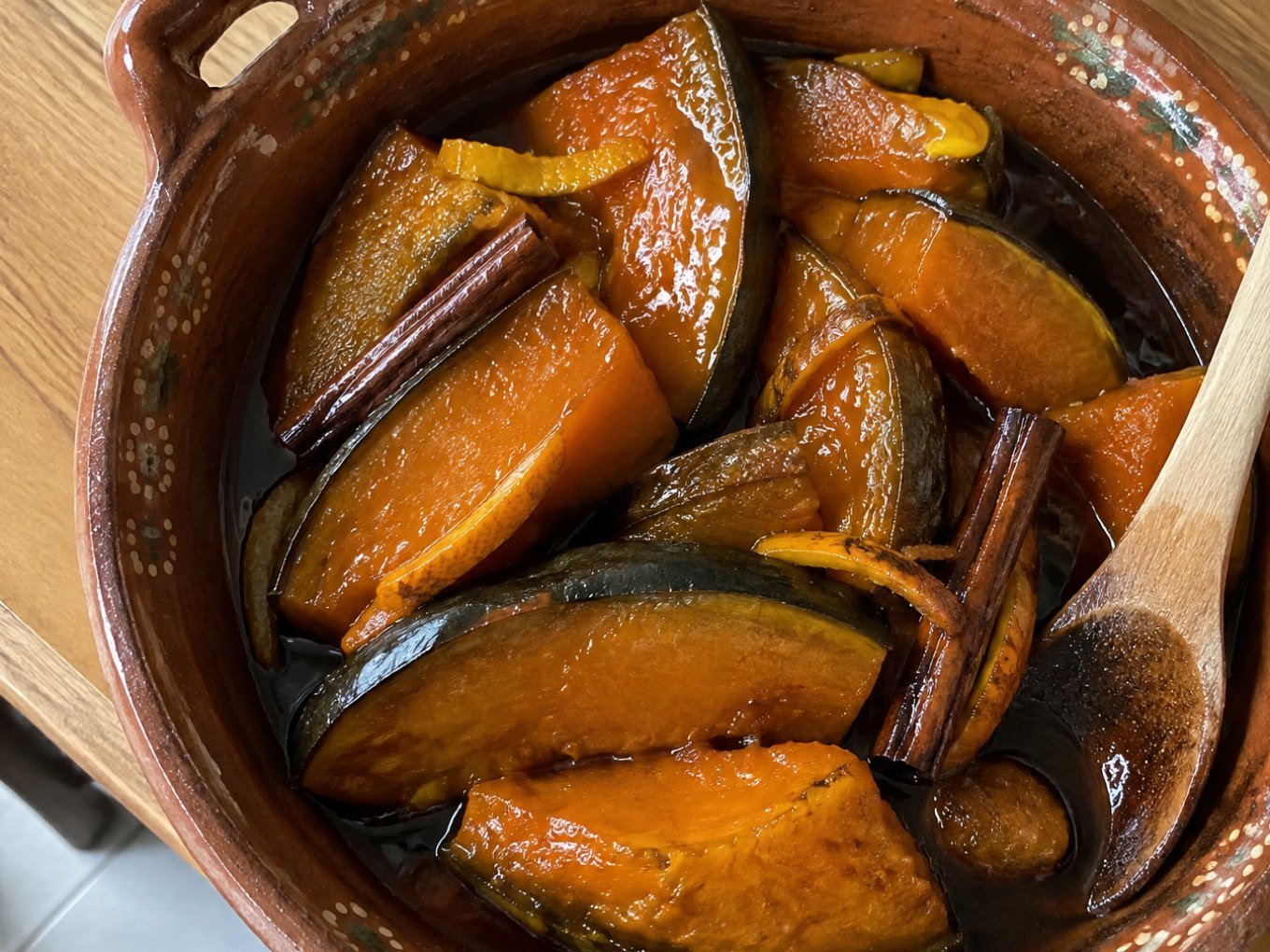 Gajos de calabaza en tacha ligera brillantes en almíbar de piloncillo con canela y naranja servidos en cazuela de barro casera