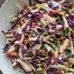 Ensalada crujiente de col morada, manzana verde, pollo deshebrado y zanahoria con aderezo cremoso de yogur y limón en tazón de cerámica
