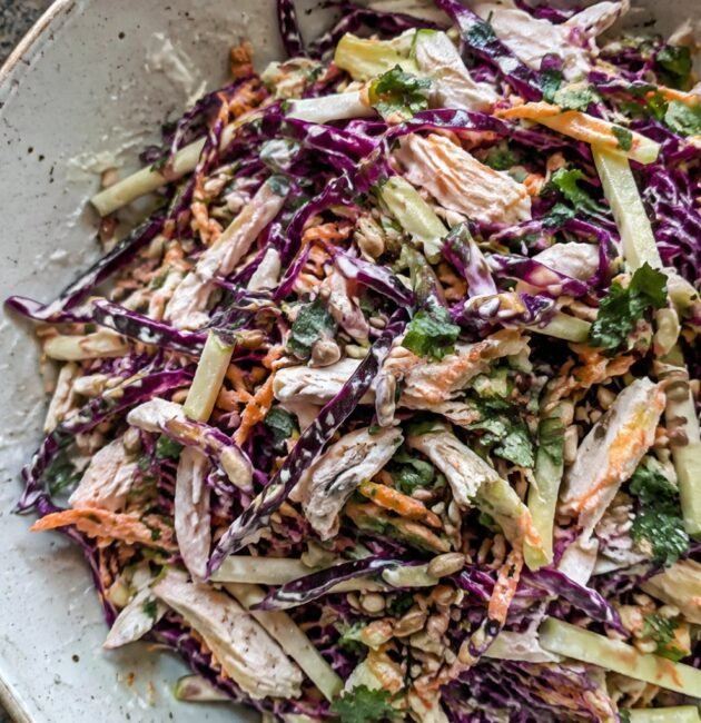 Ensalada crujiente de col morada, manzana verde, pollo deshebrado y zanahoria con aderezo cremoso de yogur y limón en tazón de cerámica