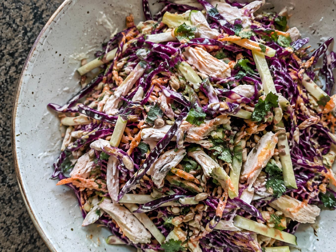 Ensalada crujiente de col morada, manzana verde, pollo deshebrado y zanahoria con aderezo cremoso de yogur y limón en tazón de cerámica