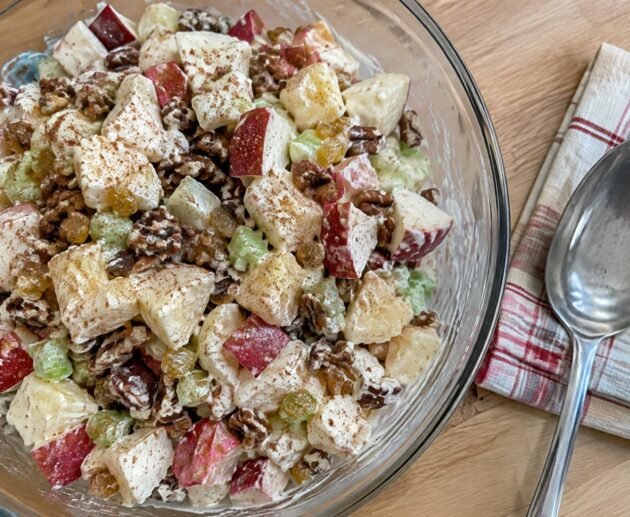 Ensalada de manzana navideña ligera con yogur griego, piña, apio, pasitas y nuez en bowl de cristal, receta fácil y saludable