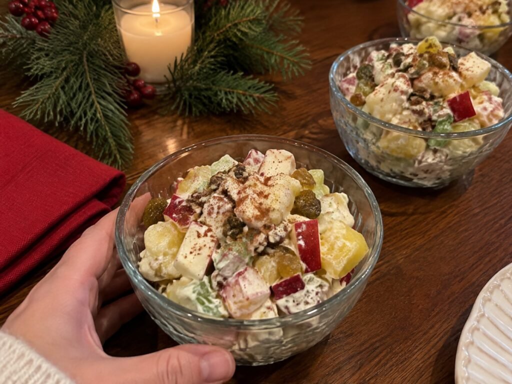 Ensalada de manzana navideña servida en bowls de cristal en la mesa de Nochebuena con servilleta roja y ramas de pino