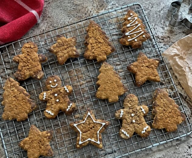 Galletas navideñas de jengibre con avena y miel enfriándose en rejilla, en forma de estrella, árbol y muñeco, receta saludable fácil