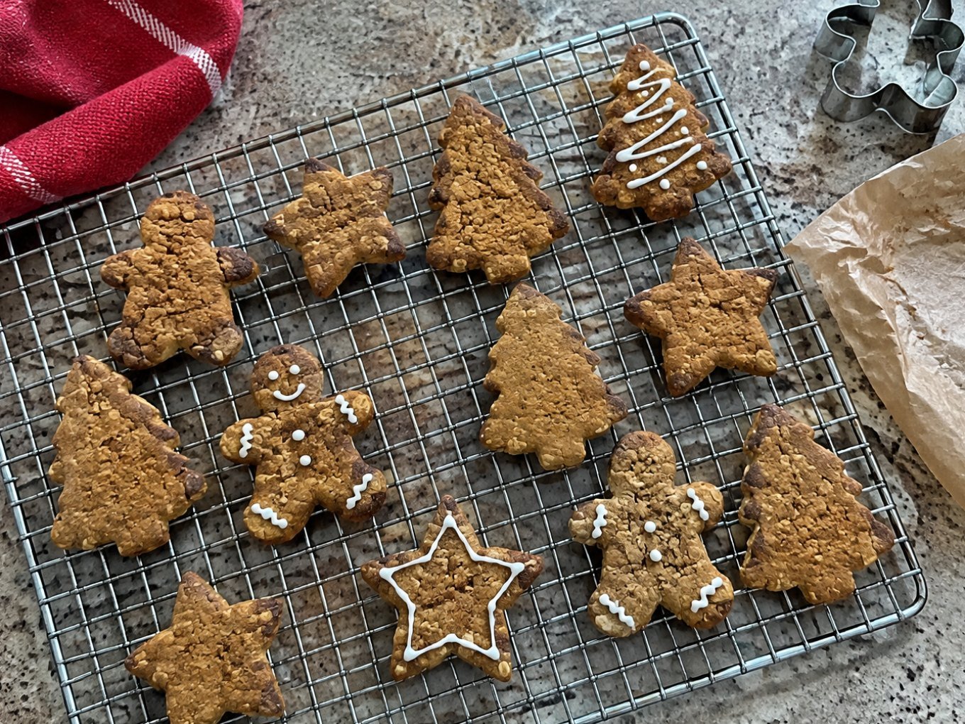 Galletas navideñas de jengibre con avena y miel enfriándose en rejilla, en forma de estrella, árbol y muñeco, receta saludable fácil