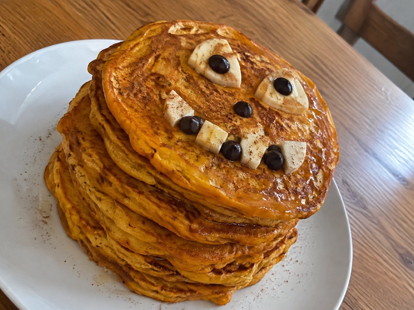Torre de hot cakes de calabaza y avena con carita de Halloween de plátano y chocolate amargo, desayuno saludable y fácil para niños