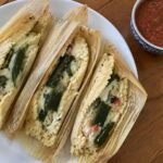 Tamales de rajas con queso sin manteca abiertos en plato blanco, masa esponjosa con chile poblano y queso derretido, receta casera