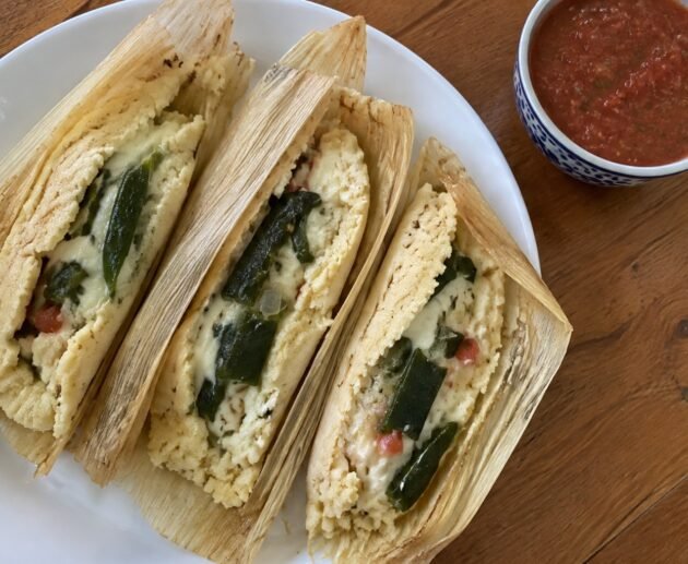 Tamales de rajas con queso sin manteca abiertos en plato blanco, masa esponjosa con chile poblano y queso derretido, receta casera