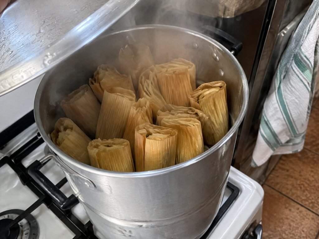 Vaporera de tamales humeante en la estufa con tamales de rajas con queso parados, cocción al vapor de tamales caseros sin manteca